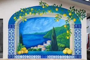 Ručni mural sa pogledom na more, limunima i plavim pločicama u mediteranskom stilu.