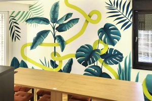 Mural sa tropskim biljkama i monstera listovima u poslovnom enterijeru, ručno oslikan zid.