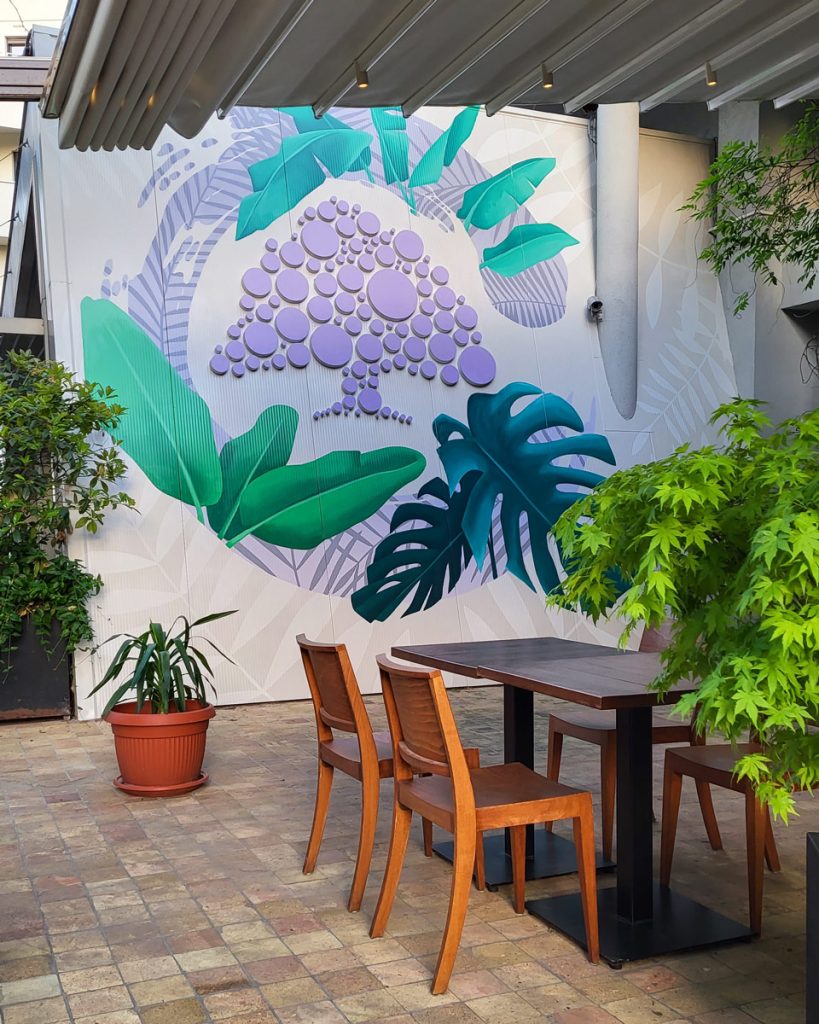 Botanički mural sa tropskim lišćem u bašti restorana