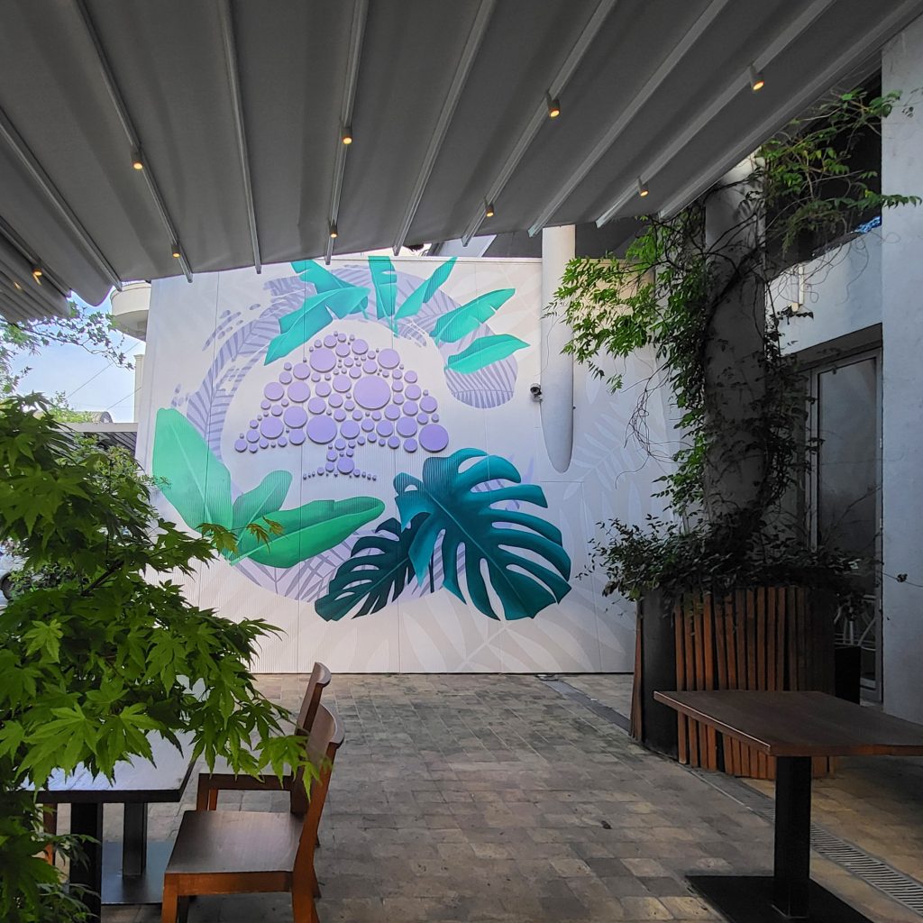 Botanički mural u bašti restorana sa motivima tropskog lišća