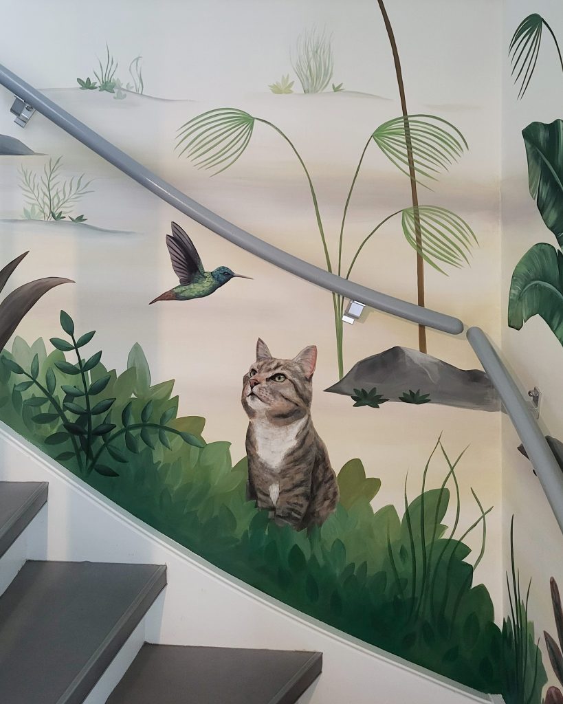 Detalj botaničkog murala sa oslikanom mačkom i kolibrijem
